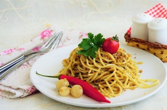 Спагетти с мясным фаршем на белой тарелке с овощами